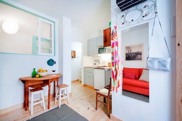A compact living space with a dining area, kitchenette, and a red sofa.