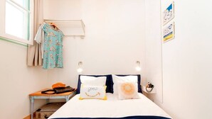 A bedroom with a bed, pillows, a hanging rack, a small table, and a suitcase. - Cozy Apartment in Historical Lisbon by COZYSTAYS 1/5 (Lisbon)
