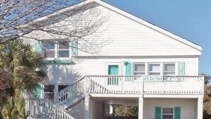 A white two-story house with a covered front porch, a staircase leading to the entrance, and two trash bins. - It'll Do Two -  Private Pool Close to Beach (North Myrtle Beach)