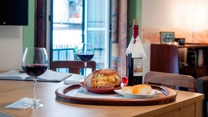 A dining table with a loaf of bread, a bottle of wine, and glasses of red wine. - Cozy Apartment in Historical Lisbon by COZYSTAYS 2/5 (Lisbon)
