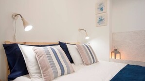 A neatly made bed with striped pillows, two wall-mounted reading lamps, and a small wall-mounted lantern. - Cozy Apartment in Historical Lisbon by COZYSTAYS 2/5 (Lisbon)