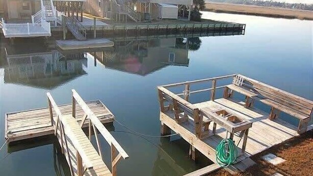 Een pand aan het water met een steiger en een huis met balkon.