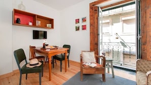 A cozy living room with a wooden dining table, green chairs, a sofa, and a balcony with a wrought iron railing. - Cozy Apartment in Historical Lisbon by COZYSTAYS 3/5 (Lisbon)