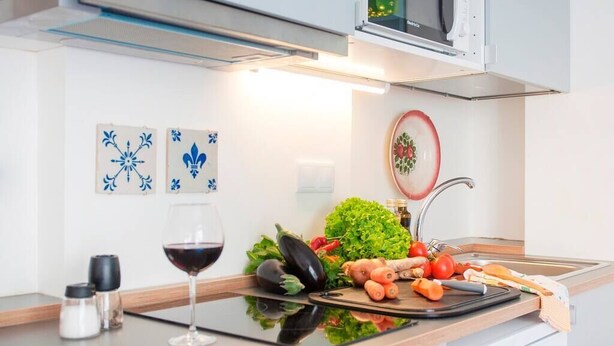 A modern kitchen with a countertop, a wine glass, and various vegetables. - Cozy Apartment in Historical Lisbon by COZYSTAYS 4/5 (Lisbon)
