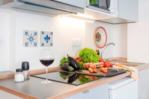 A modern kitchen with a countertop, a wine glass, and various vegetables.