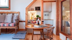 A cozy room with a wooden bed, a dining table with chairs, a kitchen area, and a large window. - Cozy Apartment in Historical Lisbon by COZYSTAYS 5/5 (Lisbon)