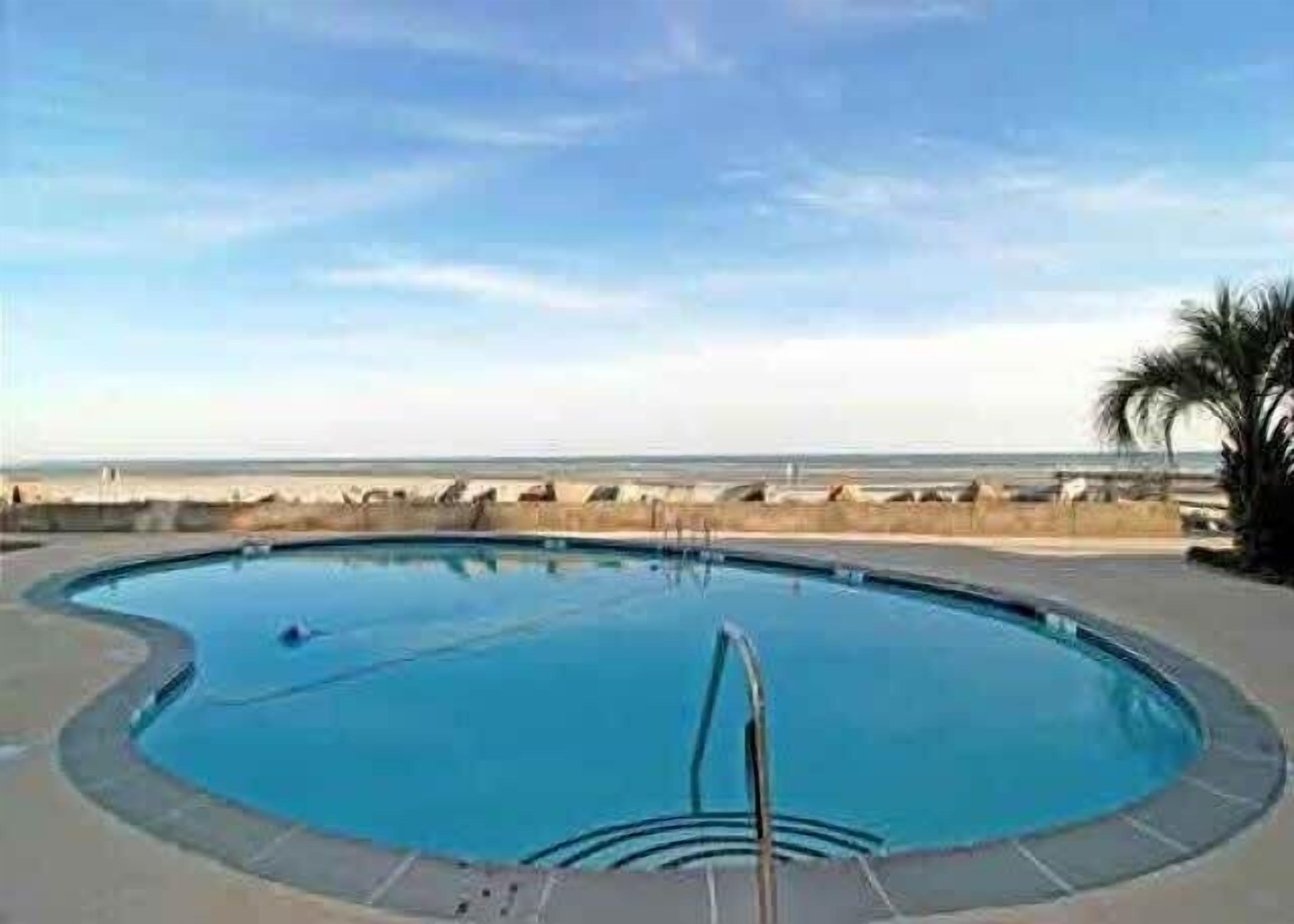 Ein Schwimmbecken mit Blick auf Strand und Meer.