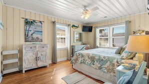 Ein Schlafzimmer mit Bett, Kommode, Fernseher und Deckenventilator.