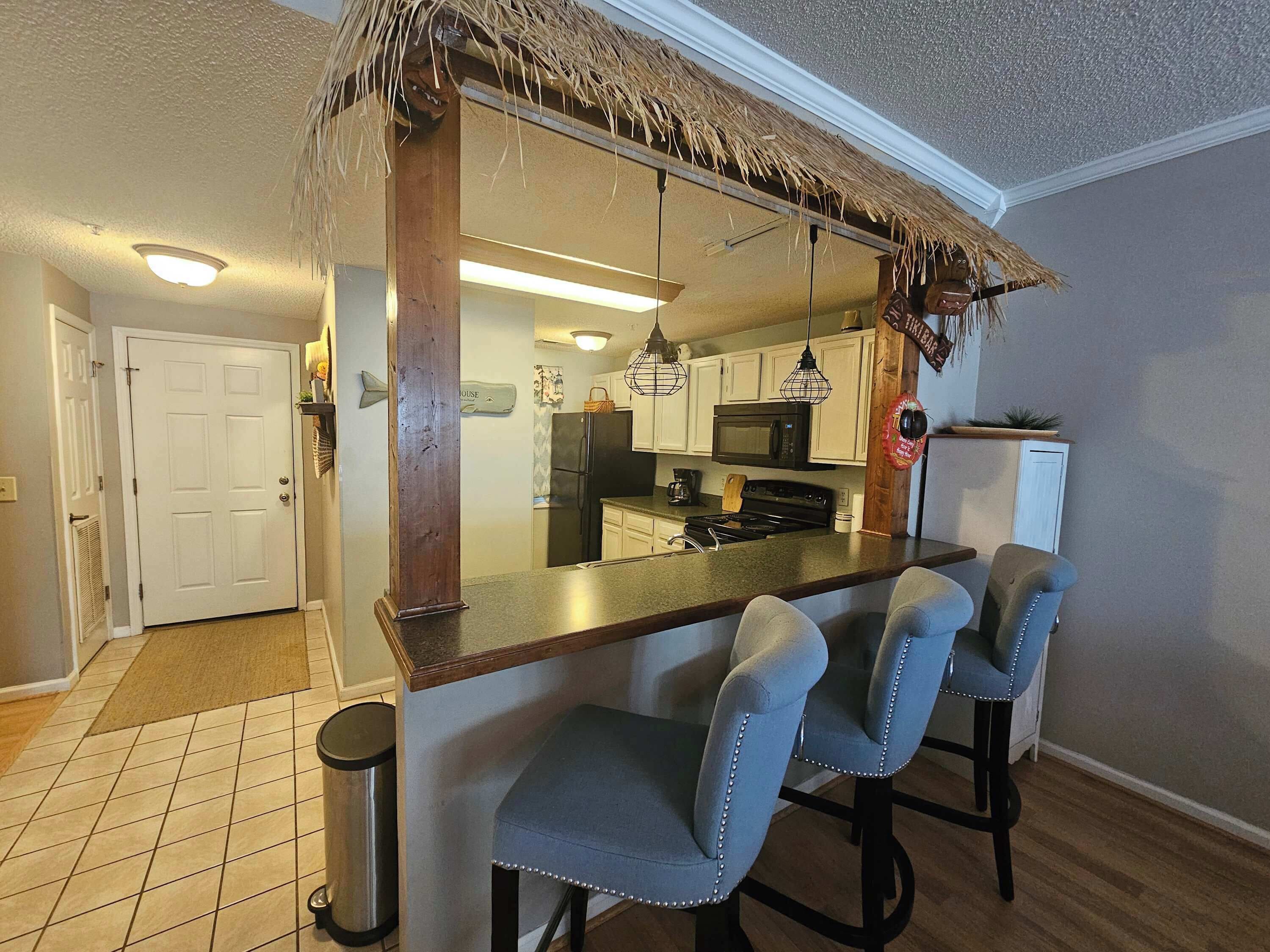 A kitchen with a bar area, a refrigerator, a microwave, and a stove.