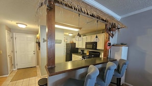A kitchen with a bar area, a refrigerator, a microwave, and a stove.