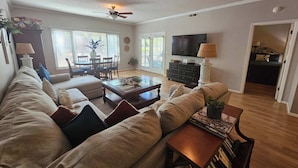 A living room with a sofa, coffee table, TV, and ceiling fans.