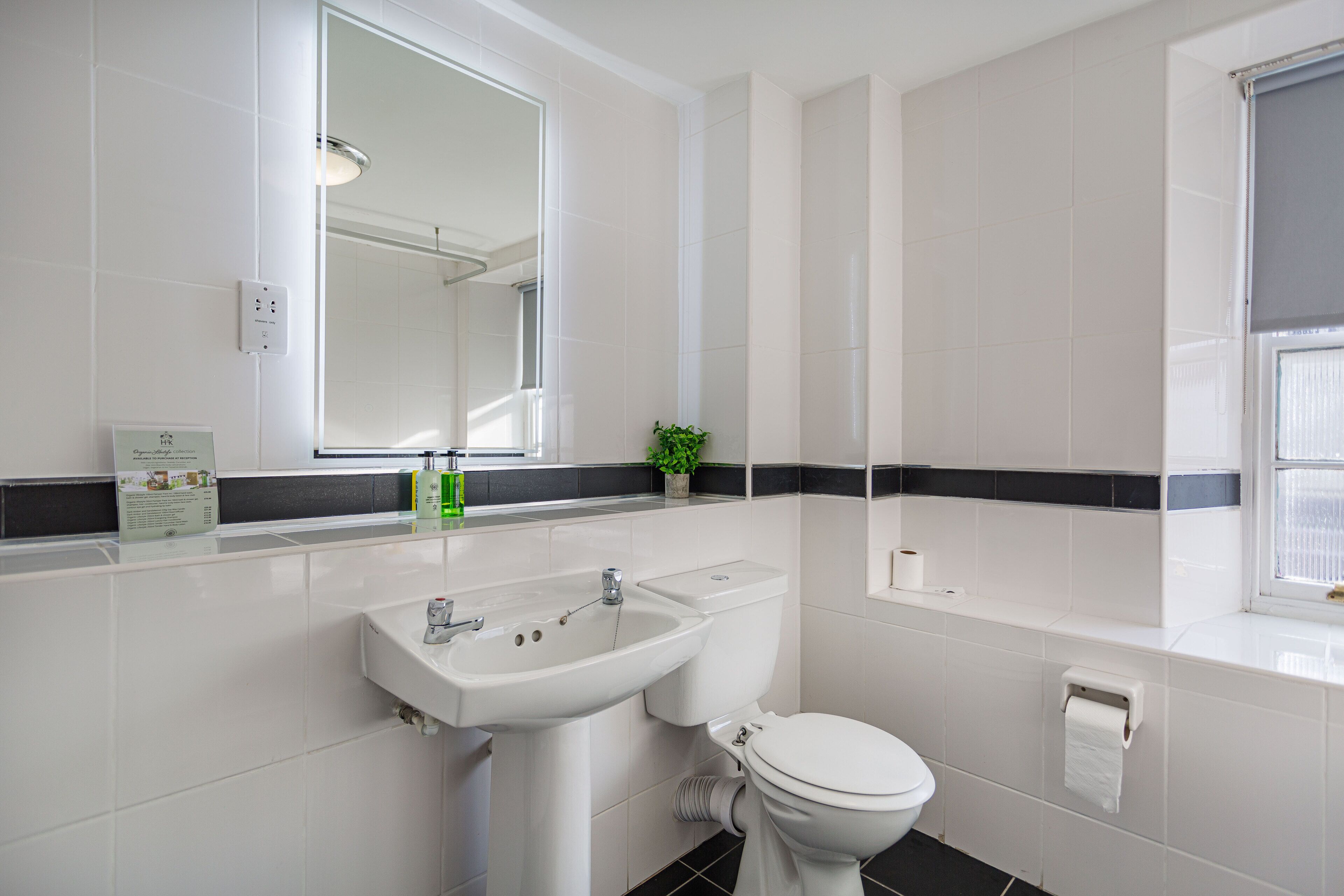 A modern bathroom with a white sink, toilet, and a large mirror.