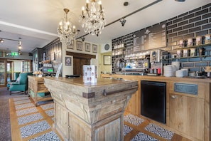 Una zona de bar con mostrador de madera, un candelabro y una pizarra de menú.