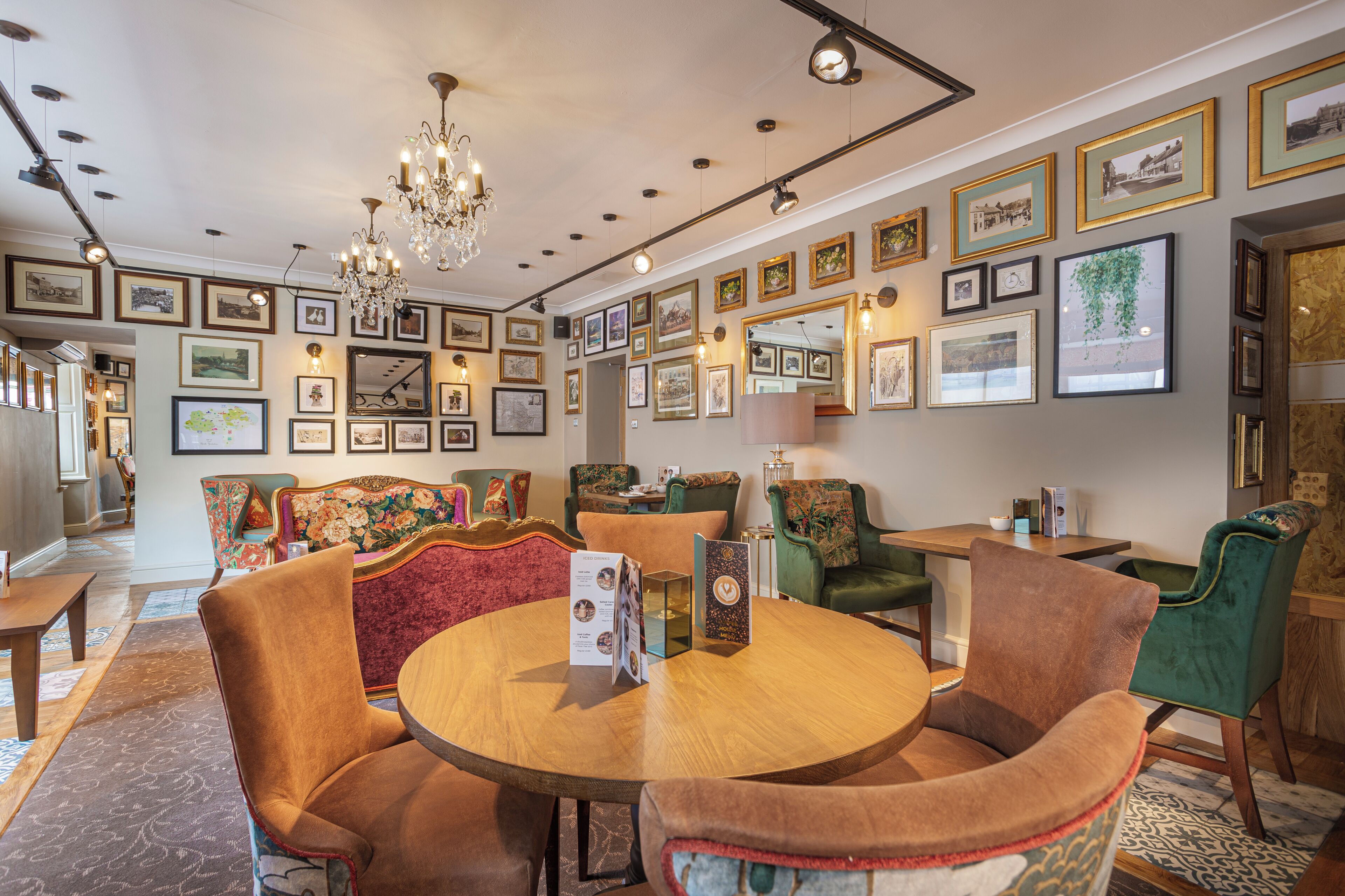 A dining area with a round table, upholstered chairs, and a chandelier.