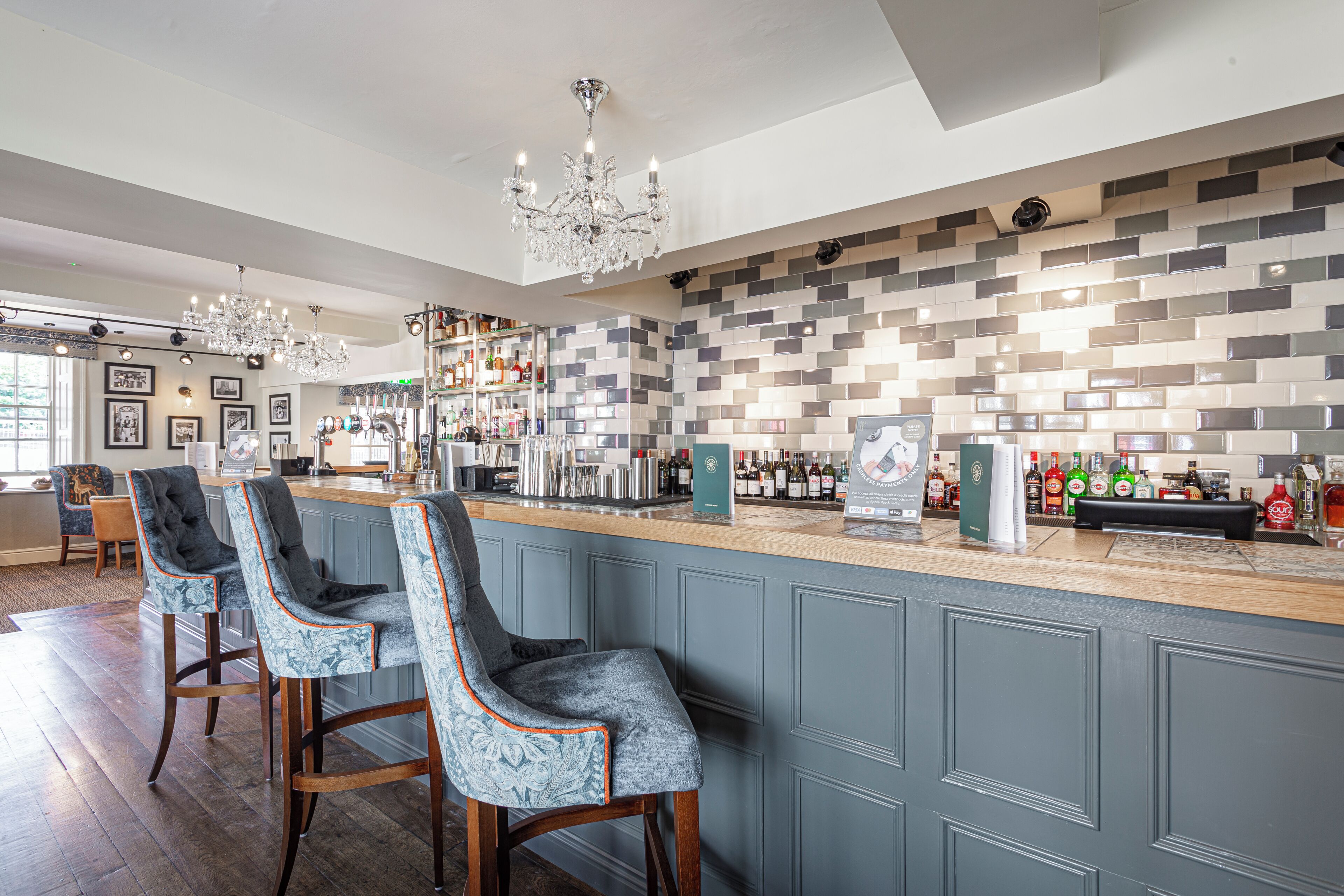 A bar area with a counter, bar stools, and a tiled wall.