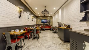 A restaurant with marble flooring, multiple tables and chairs, a television screen, and a modern light fixture. - La Porte de Taksim (Istanbul)