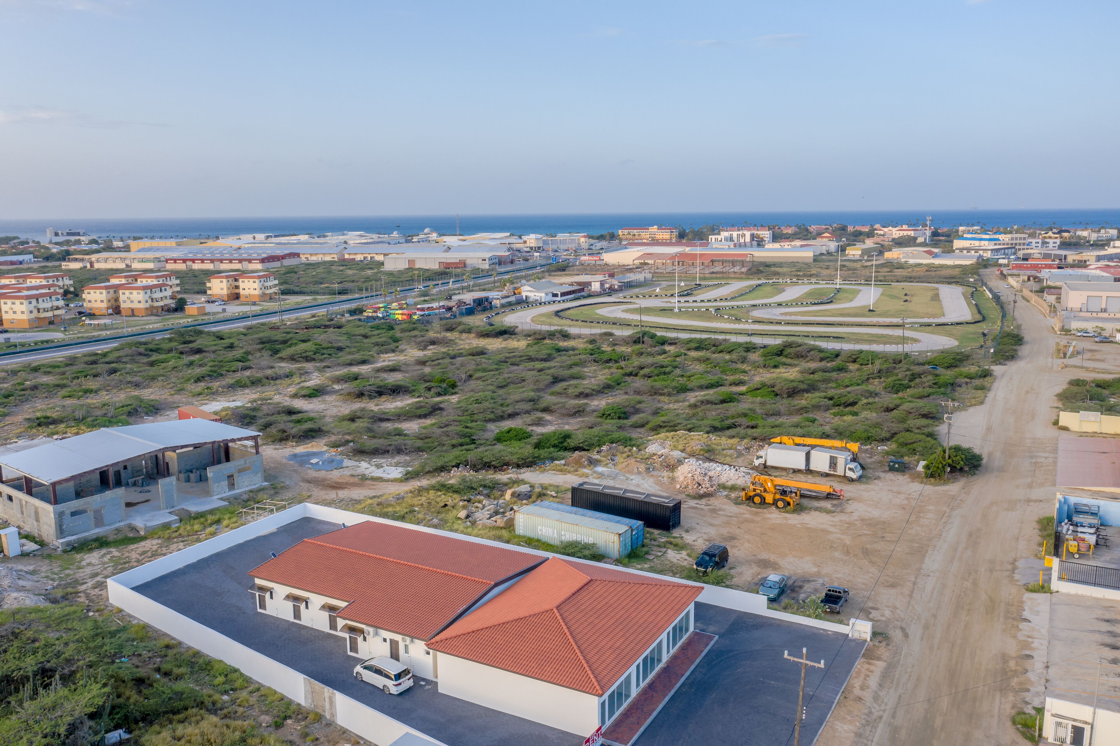 Vue aérienne d’une zone côtière avec des bâtiments, des routes et un chantier de construction.