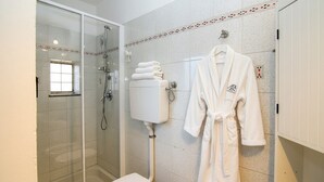 A bathroom with a glass-enclosed shower, a toilet, and a sink. A white robe is hanging on the wall. - Casa Baia Salata 2 (Imperia)