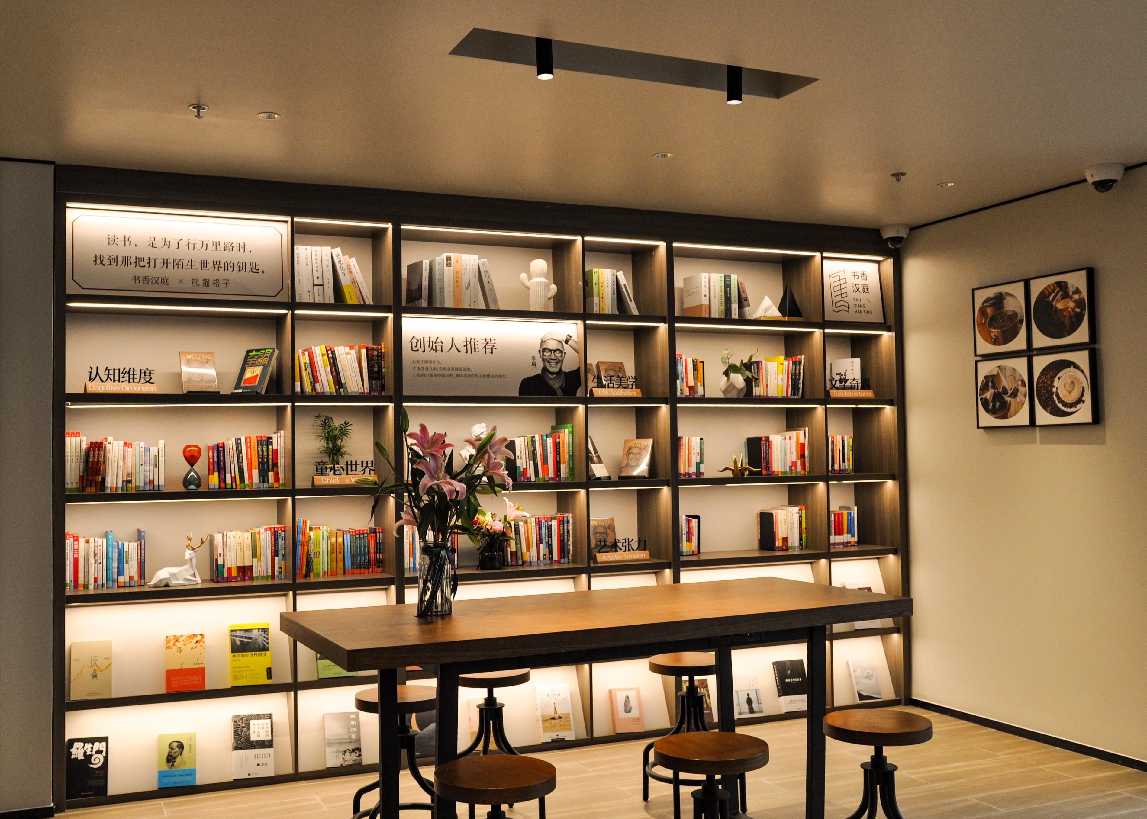 Et moderne bibliotek med reoler, et centralt bord og barstole.