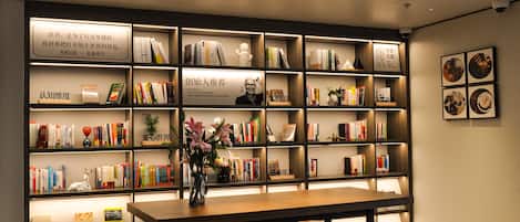 Eine moderne Bibliothek mit Bücherregalen, einem zentralen Tisch und Hockstühlen.