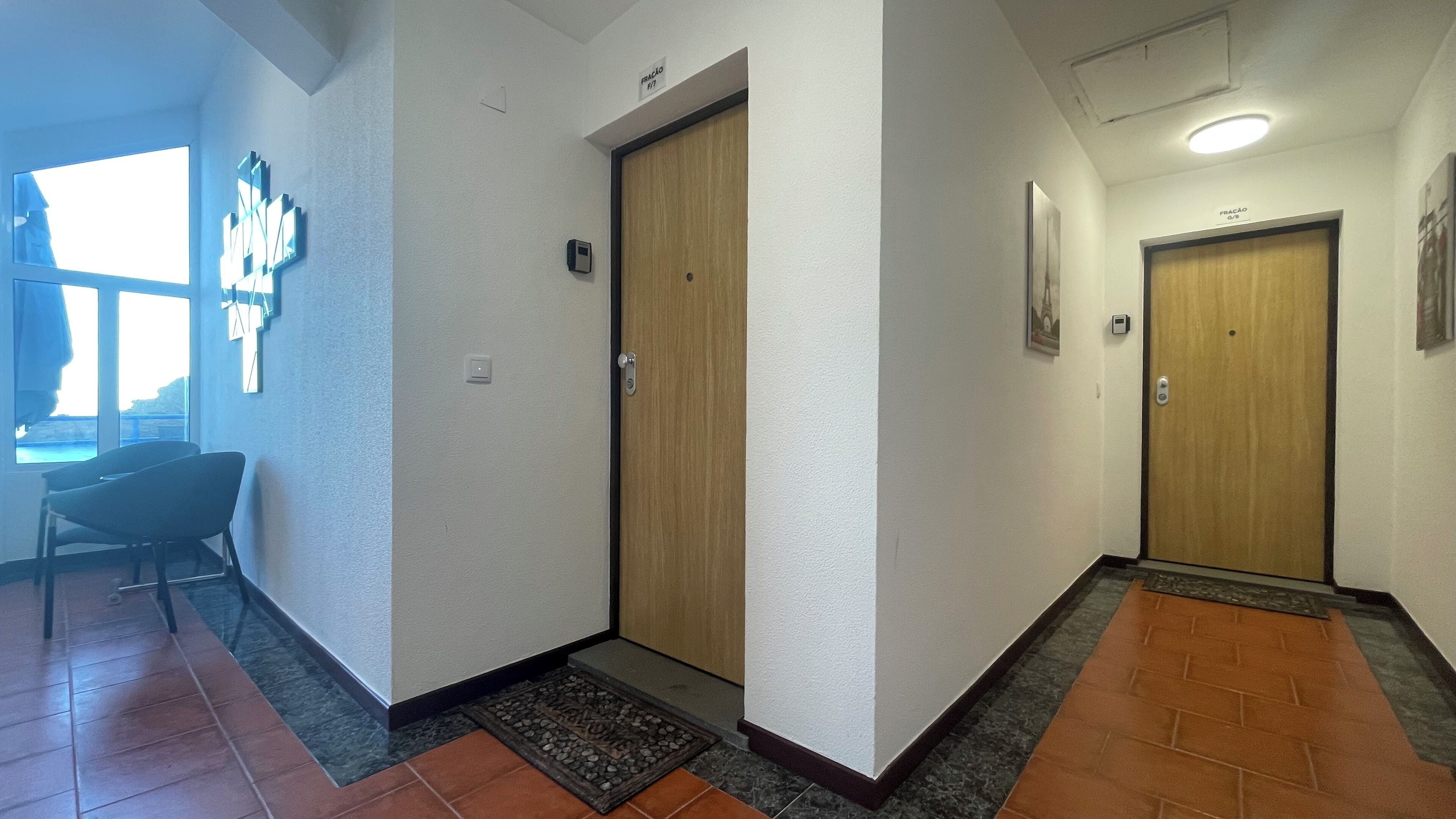A hallway with wooden doors, a small desk, and a window with a view.