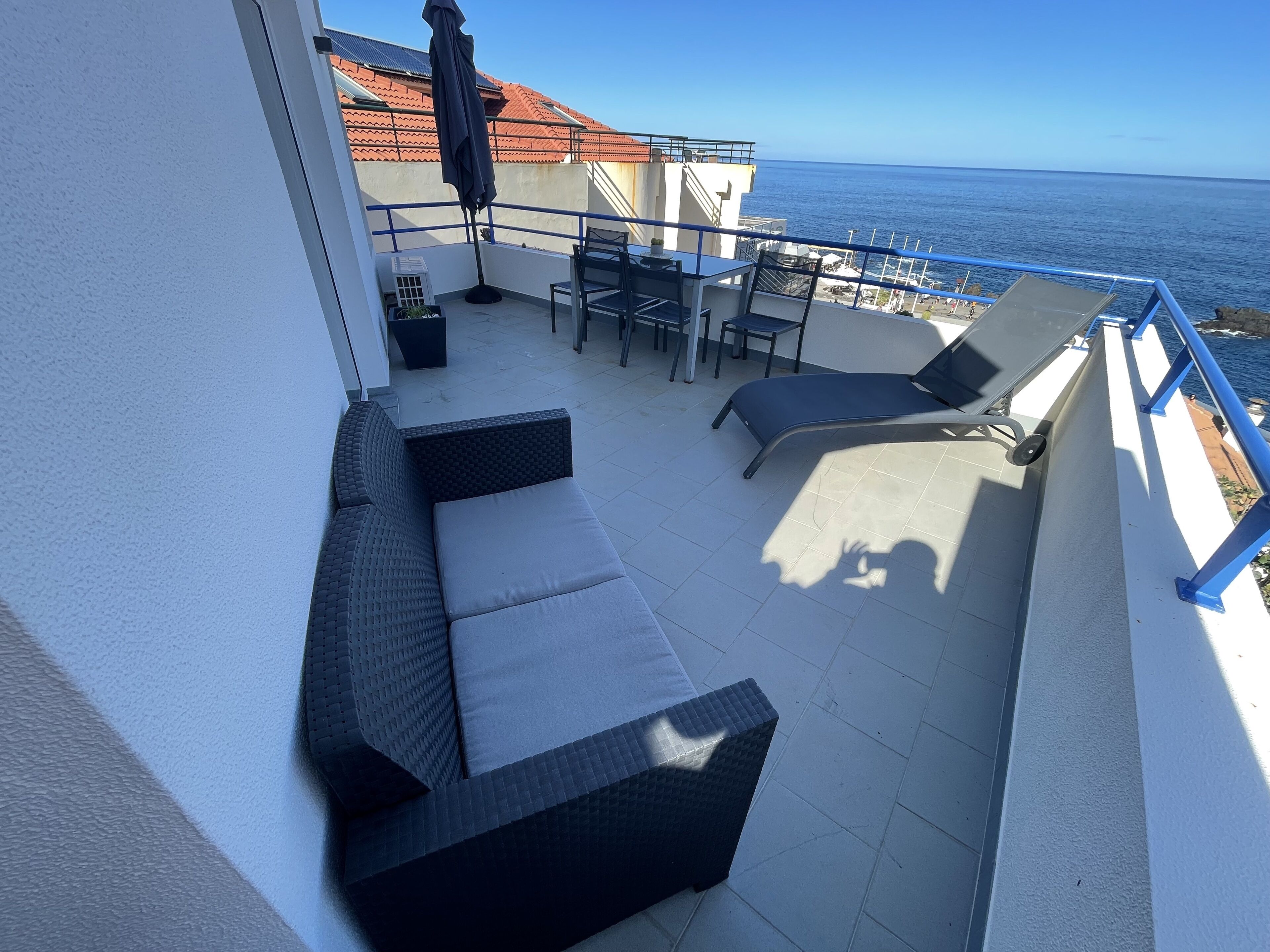 Un balcon avec un canapé, des chaises et une table, donnant sur la mer.