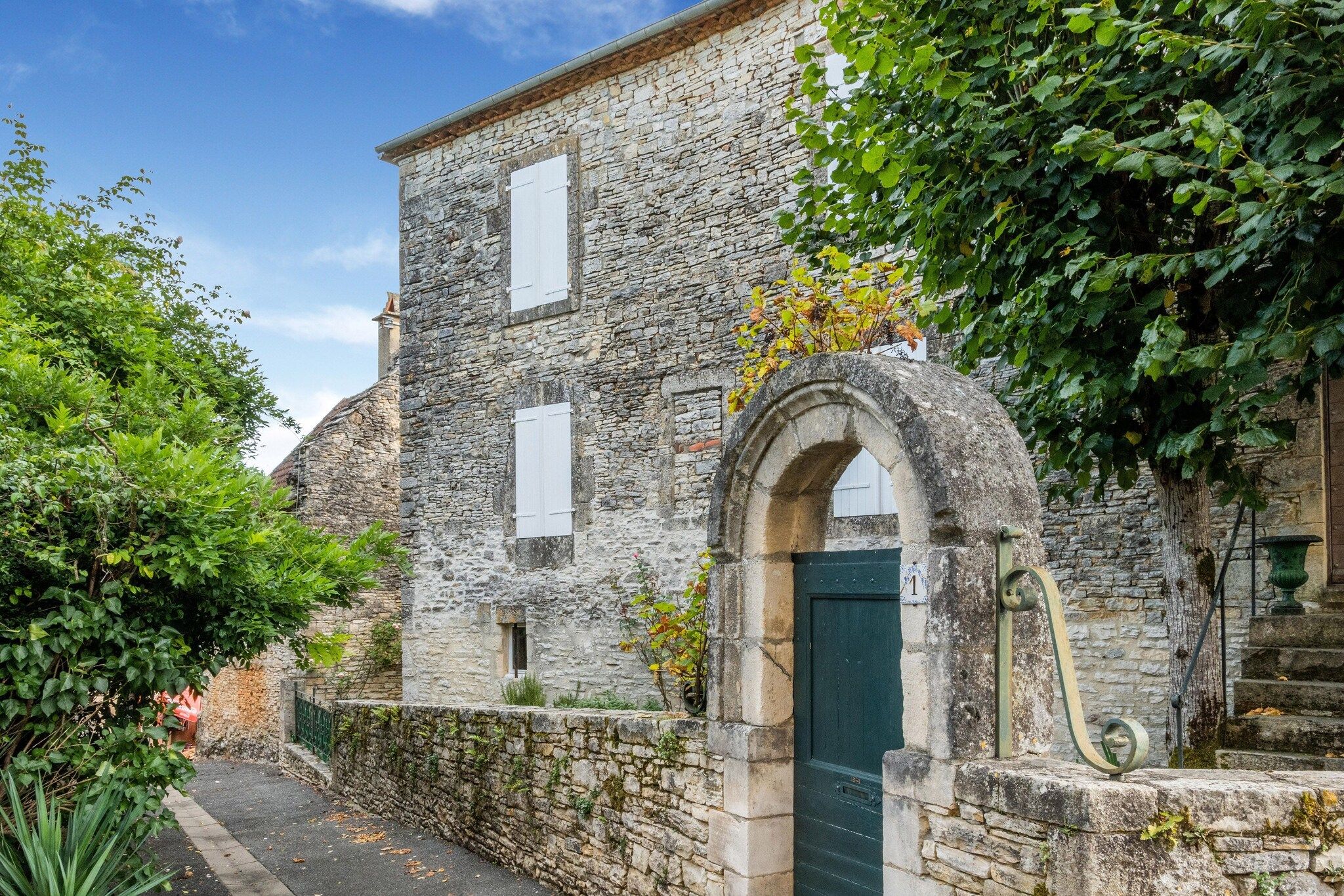A stone building with a green door, a small window, and a stone archway.