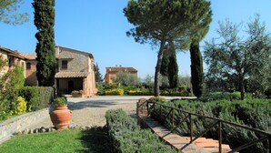 A traditional stone building with a tiled roof, surrounded by well-maintained gardens and a gravel pathway leading to a wooden bridge. - Hideaway Near San Gimignano (Castelfiorentino (FI))