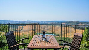 A wooden table with a bottle and glass on a balcony overlooking a vineyard. - Hideaway Near San Gimignano (Castelfiorentino (FI))