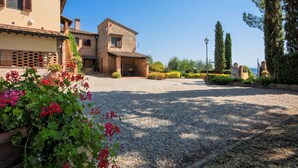A courtyard with a gravel path, a building with a tiled roof, and a garden with red flowers. - Hideaway Near San Gimignano (Castelfiorentino (FI))
