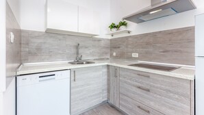 Una cocina moderna con armarios de madera gris, lavavajillas integrado y un lavamanos de acero inoxidable.