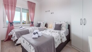 Un dormitorio con dos camas, un armario y una ventana con cortinas rosadas.