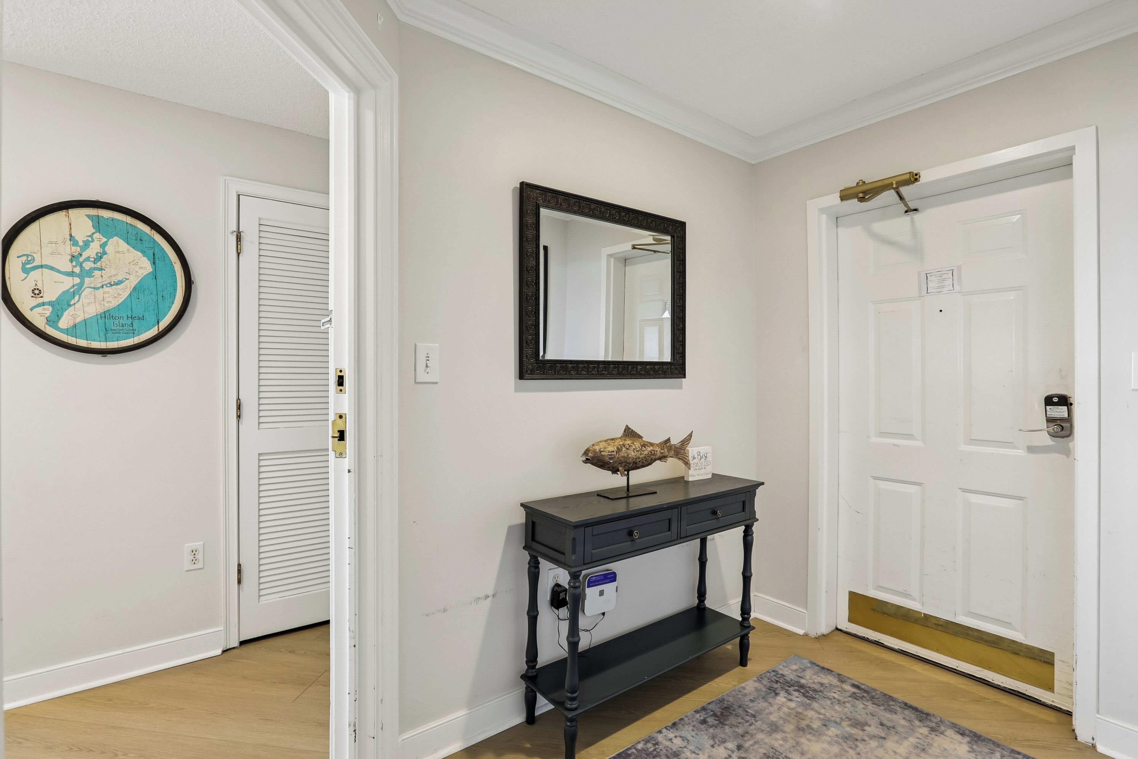 A hallway with a map, a mirror, a fish sculpture, and a door with a keypad lock.