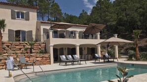 A two-story building with a pool area, including lounge chairs and umbrellas.