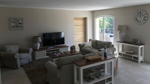 A living room with a flat-screen TV, a sofa, a coffee table, and a side table with a lamp.