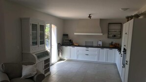 A modern kitchen with white cabinets, a built-in oven, and a dining area with a sofa and a table.