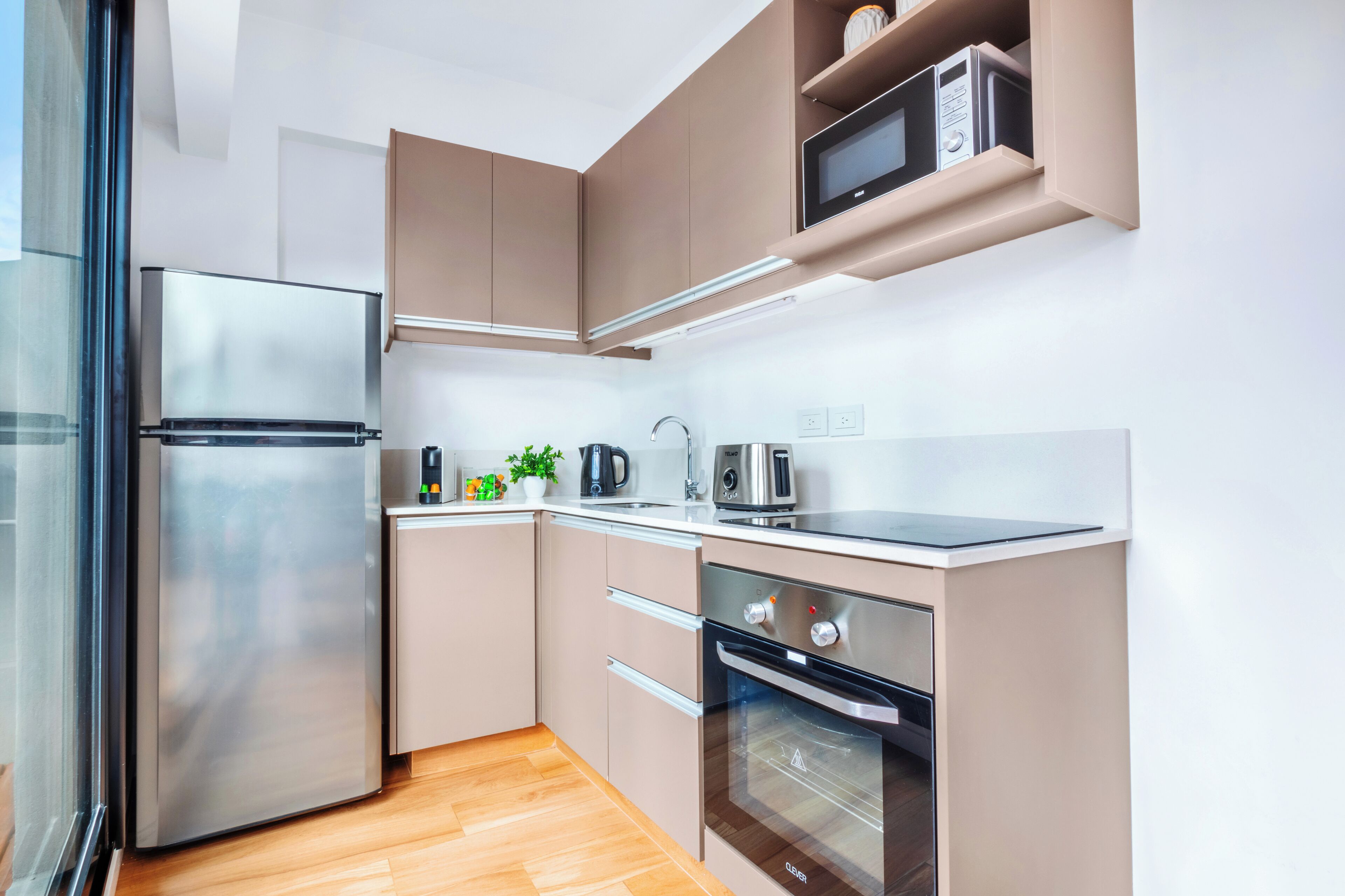 A modern kitchen with stainless steel appliances, wooden flooring, and built-in cabinets.