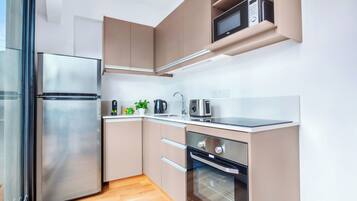 A modern kitchen with stainless steel appliances, wooden flooring, and built-in cabinets.