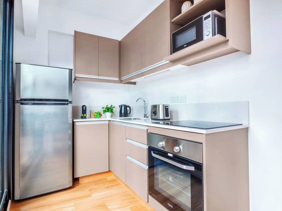 A modern kitchen with stainless steel appliances, wooden flooring, and built-in cabinets.