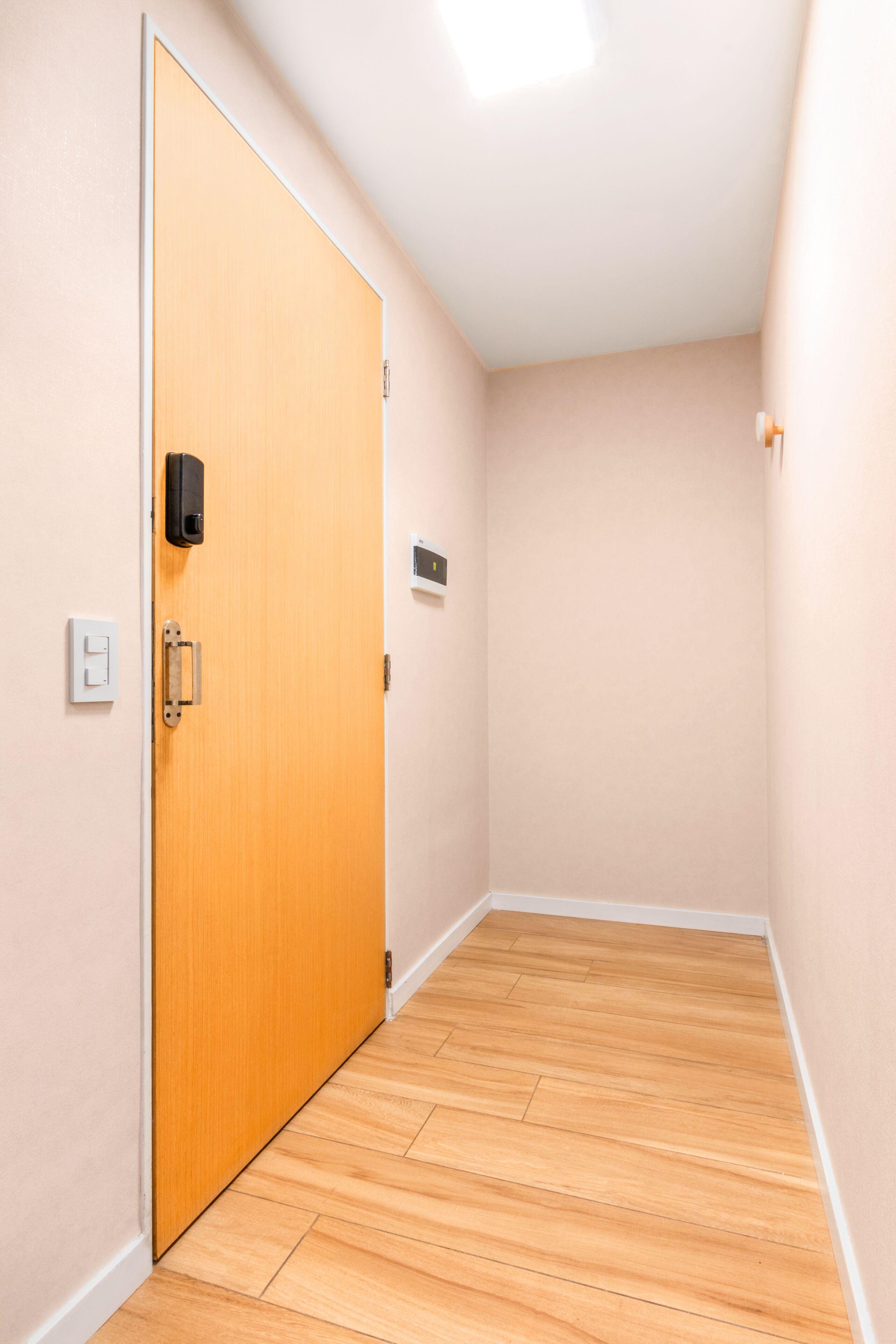 Un couloir étroit avec un plancher en bois et des murs de couleur beige.
