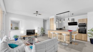 A modern apartment with a living room, kitchen, and dining area. It features a sofa, a TV, a dining table, and a kitchen counter with bar stools. - Beautiful And Spacious Apt At 19 Min From Downtown (Toulouse)