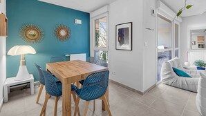A dining area with a wooden table and blue chairs, a white lamp, and decorative wall art. - Beautiful And Spacious Apt At 19 Min From Downtown (Toulouse)