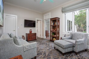A living room with a sectional sofa, a chaise lounge, a wooden bookcase, and a television on the wall.