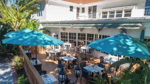 An outdoor patio with tables and chairs, surrounded by greenery and umbrellas. - Shangri-La Springs (Bonita Springs)