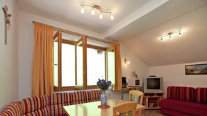 Uma sala de estar acolhedora com um sofá, uma mesa de jantar e uma televisão.