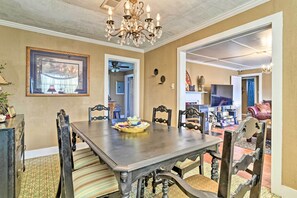 Enjoy meals in this elegant dining room with a large table and six chairs, a chandelier, and a framed picture above.