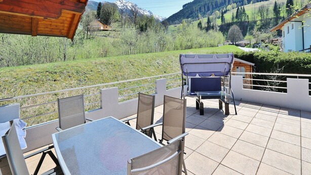 A terrace with a table and chairs overlooking a mountainous landscape. - Apartment in Niedernsill near Ski Slopes (Niedernsill)