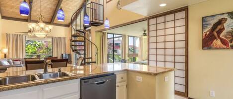 A kitchen with a central island, a dishwasher, and a spiral staircase.