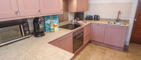 A kitchen with pink cabinets, a microwave, a toaster, and a sink.