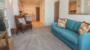 Una sala de estar con un sofá azul, un sillón de cuero marrón y una mesita.